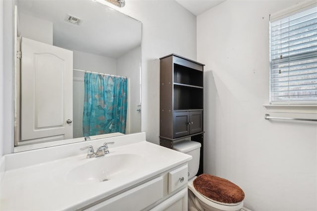 bathroom featuring walk in shower, vanity, toilet, and a wealth of natural light