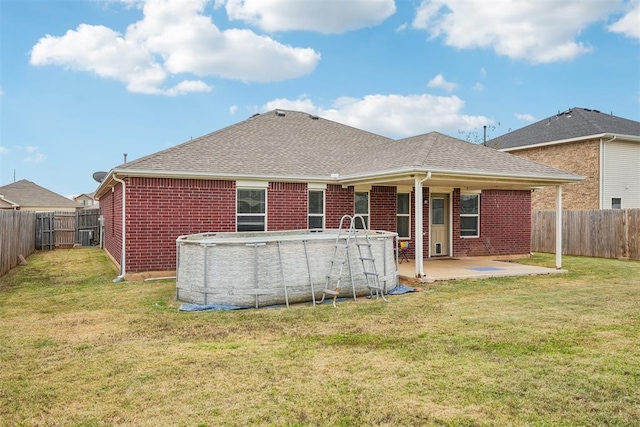 back of house with a fenced in pool, a patio area, and a lawn