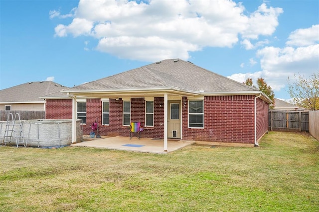 rear view of property with a fenced in pool, a patio, and a yard