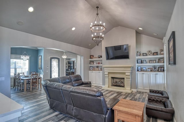 living room featuring built in features, lofted ceiling, dark wood-type flooring, and a chandelier