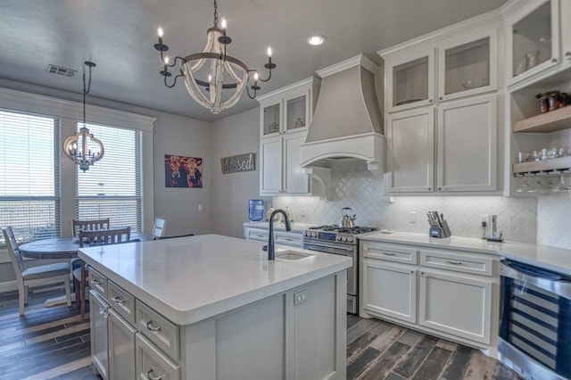 kitchen with premium range hood, high end stainless steel range oven, beverage cooler, sink, and hanging light fixtures