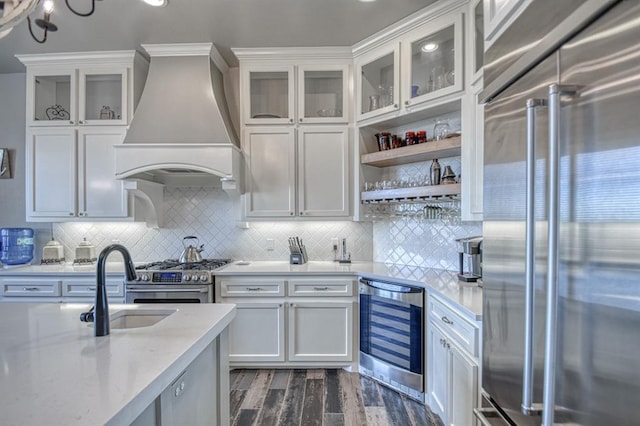 kitchen with backsplash, premium range hood, beverage cooler, sink, and high quality appliances