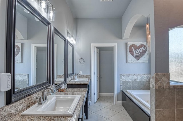 bathroom featuring tile patterned flooring, vanity, and a relaxing tiled tub