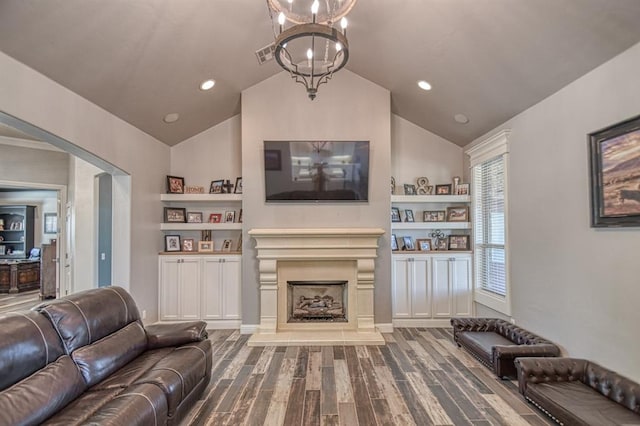 living room with built in shelves, hardwood / wood-style floors, a chandelier, and vaulted ceiling