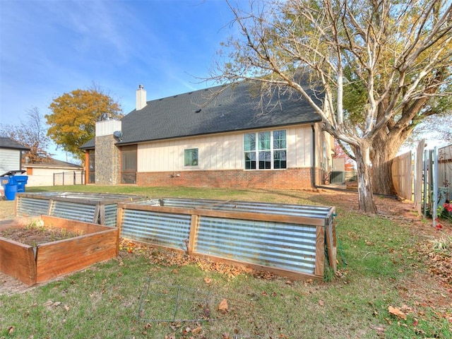 rear view of property featuring a lawn and cooling unit