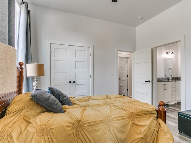 bedroom with ensuite bathroom, a closet, and light hardwood / wood-style floors