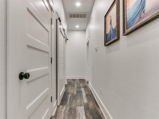 hall with a barn door and wood-type flooring