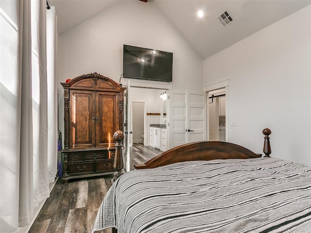 bedroom with connected bathroom, high vaulted ceiling, and dark wood-type flooring