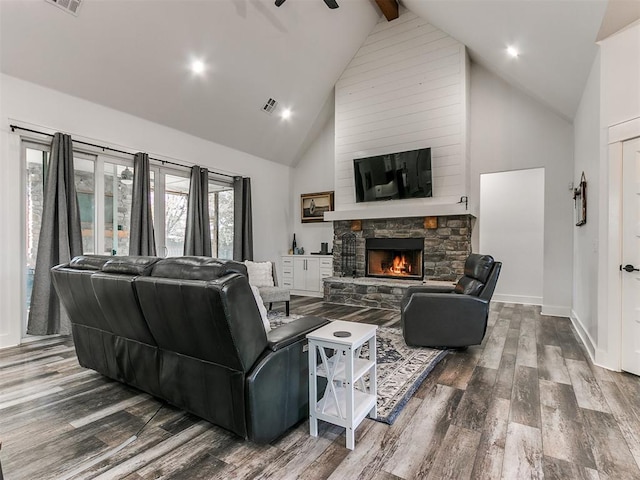 living room featuring ceiling fan, hardwood / wood-style flooring, high vaulted ceiling, beamed ceiling, and a stone fireplace