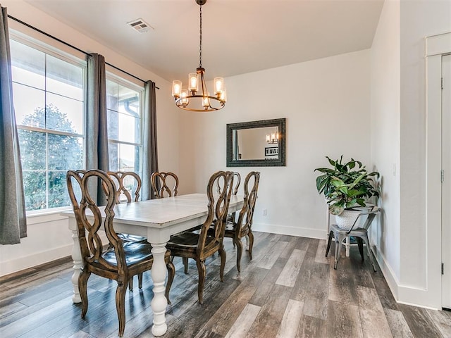 dining area with dark hardwood / wood-style floors, a healthy amount of sunlight, and a notable chandelier