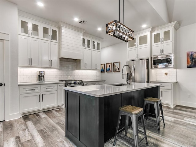 kitchen with white cabinets, appliances with stainless steel finishes, and a kitchen island with sink