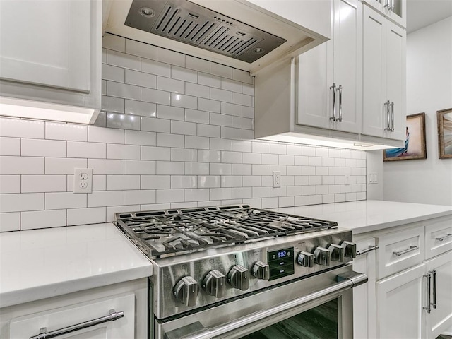 kitchen with white cabinetry, light stone countertops, high end stove, extractor fan, and decorative backsplash