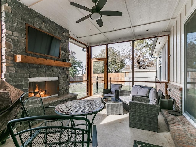 sunroom / solarium with an outdoor stone fireplace and ceiling fan