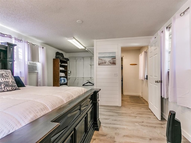 bedroom featuring a textured ceiling, light wood-type flooring, and cooling unit