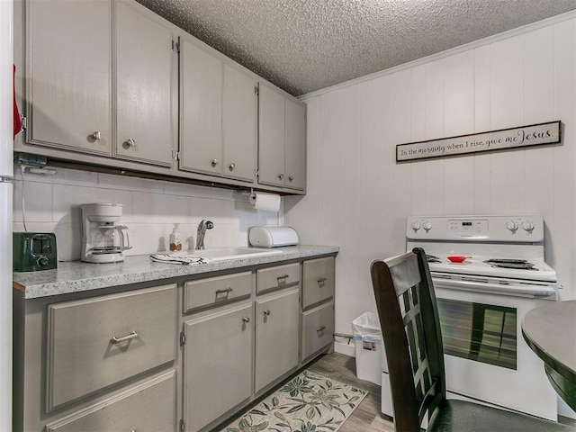 kitchen featuring sink, light wood-type flooring, a textured ceiling, and white electric range