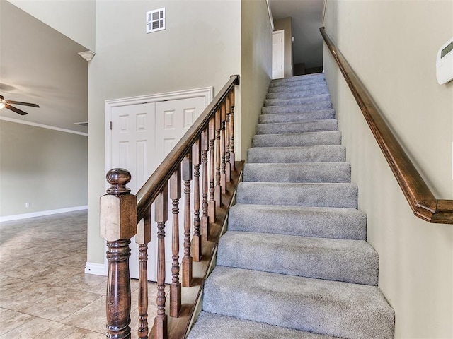 stairs with tile patterned floors, ceiling fan, ornamental molding, and a high ceiling