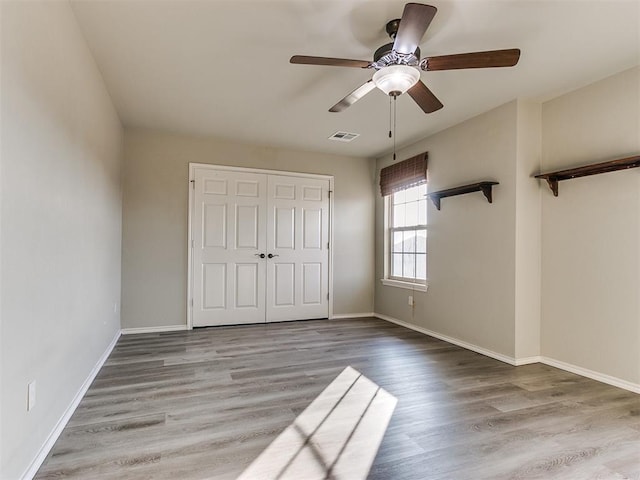 unfurnished bedroom featuring ceiling fan, a closet, and hardwood / wood-style flooring