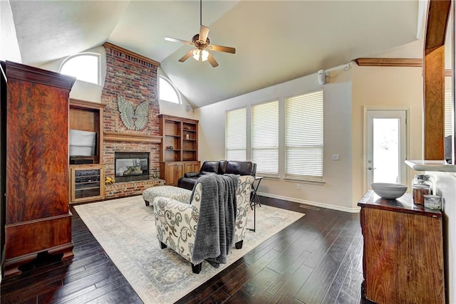 living room featuring high vaulted ceiling, a brick fireplace, ceiling fan, and dark wood-type flooring