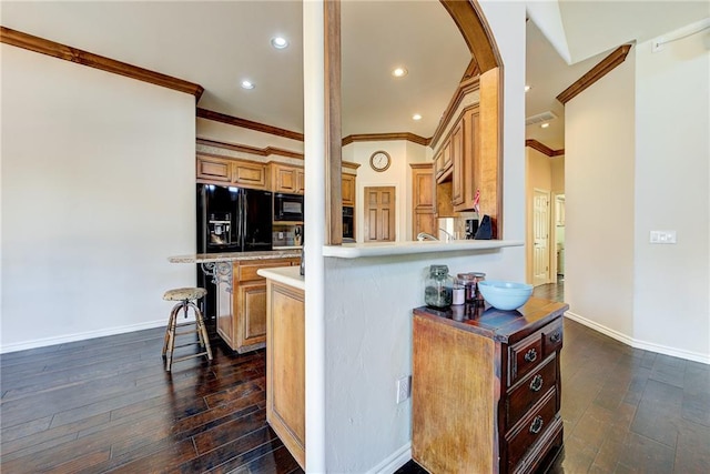 kitchen with kitchen peninsula, a kitchen breakfast bar, ornamental molding, dark wood-type flooring, and black appliances