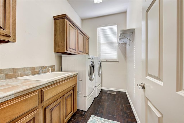 laundry area with cabinets, separate washer and dryer, sink, and dark wood-type flooring