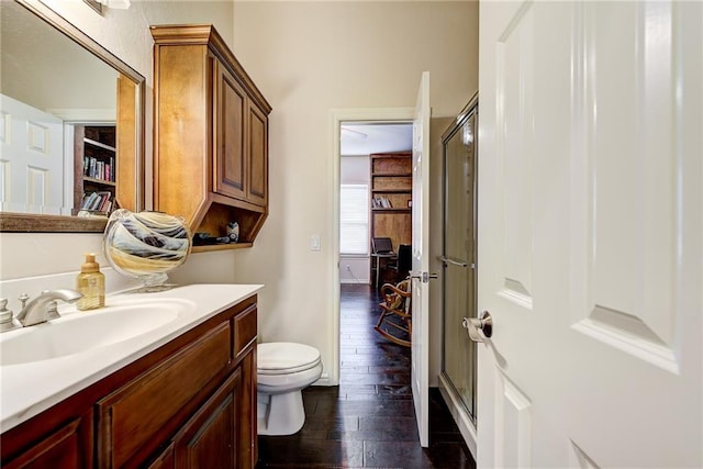 bathroom featuring hardwood / wood-style flooring, vanity, toilet, and a shower with door