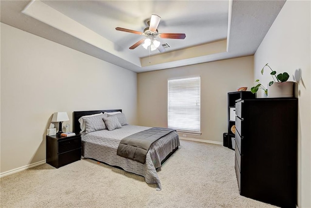 carpeted bedroom featuring ceiling fan and a raised ceiling