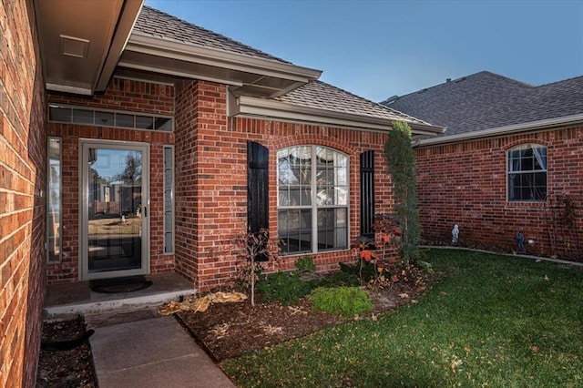 view of exterior entry featuring a lawn