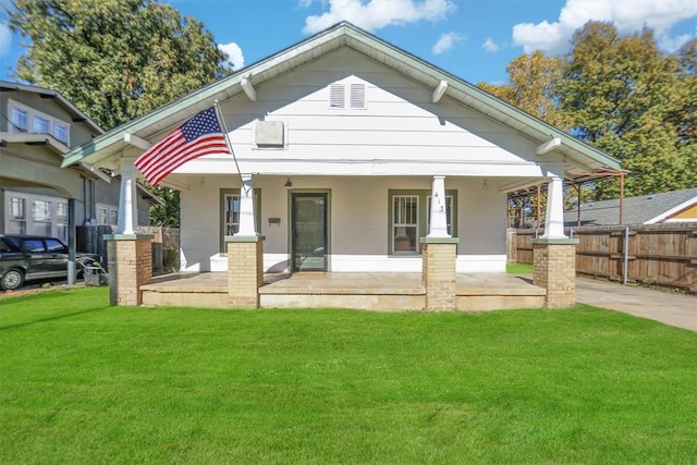 rear view of property featuring covered porch and a yard