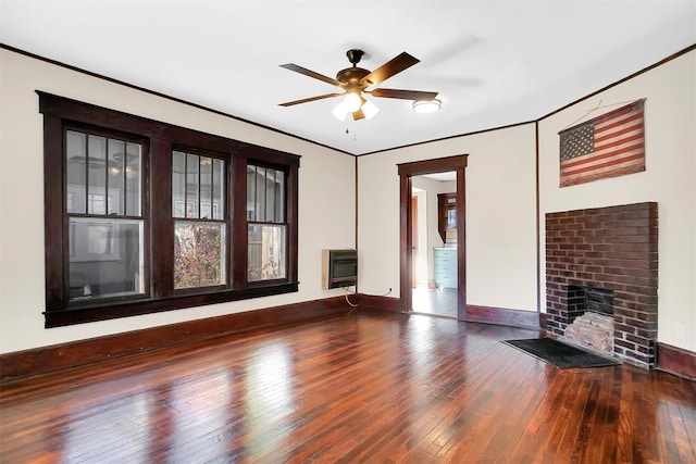 unfurnished living room featuring ceiling fan, a brick fireplace, dark hardwood / wood-style flooring, heating unit, and crown molding