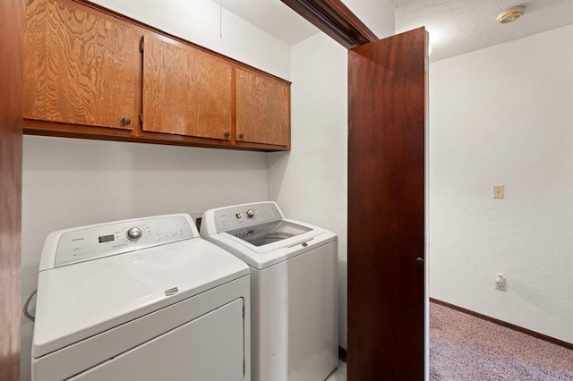 laundry room featuring washer and dryer, light colored carpet, and cabinets