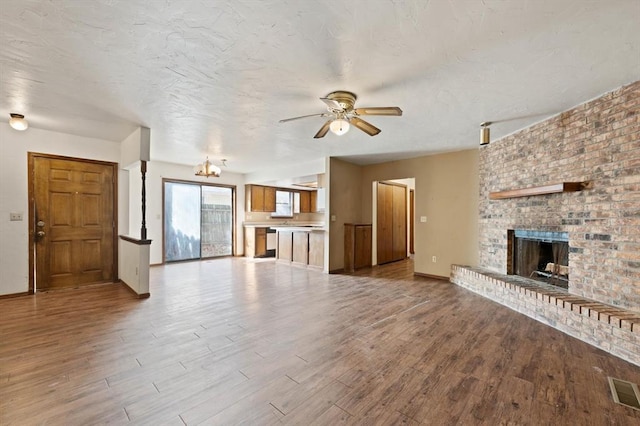 unfurnished living room with ceiling fan, a fireplace, and light hardwood / wood-style floors