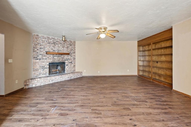 unfurnished living room featuring hardwood / wood-style flooring, ceiling fan, a fireplace, and a textured ceiling