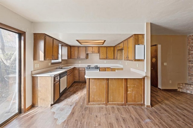 kitchen with kitchen peninsula, sink, electric stove, light hardwood / wood-style flooring, and dishwasher