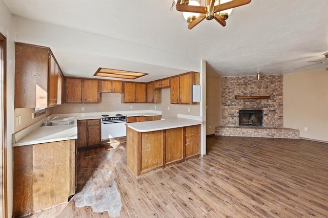 kitchen with white oven, a large fireplace, ceiling fan, and light hardwood / wood-style flooring