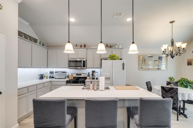 kitchen with a center island with sink, light hardwood / wood-style floors, hanging light fixtures, and appliances with stainless steel finishes