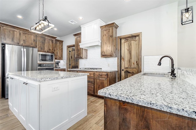 kitchen featuring decorative backsplash, appliances with stainless steel finishes, light wood-type flooring, sink, and white cabinetry