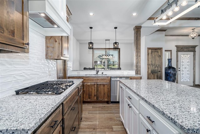 kitchen featuring appliances with stainless steel finishes, premium range hood, a kitchen island, hardwood / wood-style floors, and white cabinetry