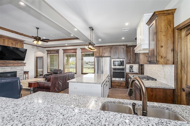 kitchen featuring sink, crown molding, ceiling fan, appliances with stainless steel finishes, and light stone counters