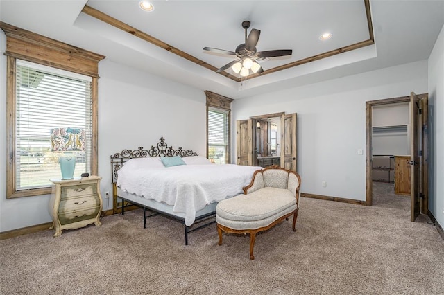 carpeted bedroom featuring ceiling fan, a raised ceiling, and multiple windows