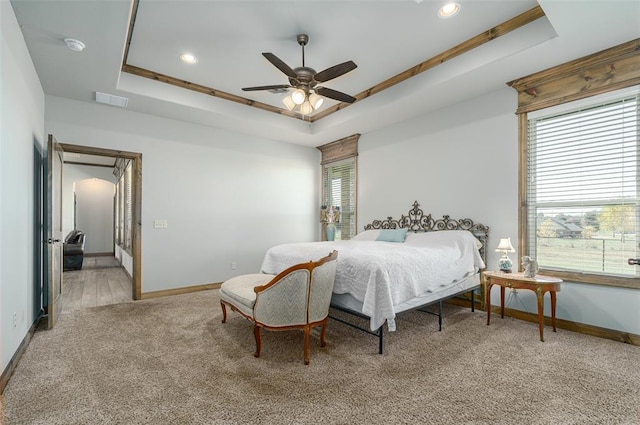 bedroom with carpet, a raised ceiling, and ceiling fan