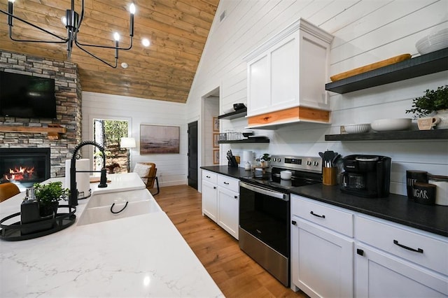 kitchen with stainless steel range with electric stovetop, light hardwood / wood-style floors, white cabinets, and sink