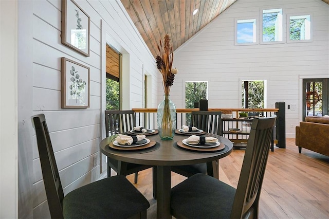 dining area with high vaulted ceiling, a healthy amount of sunlight, and light hardwood / wood-style floors