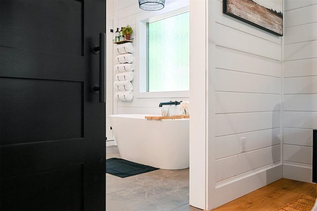 bathroom featuring wood-type flooring and a tub to relax in