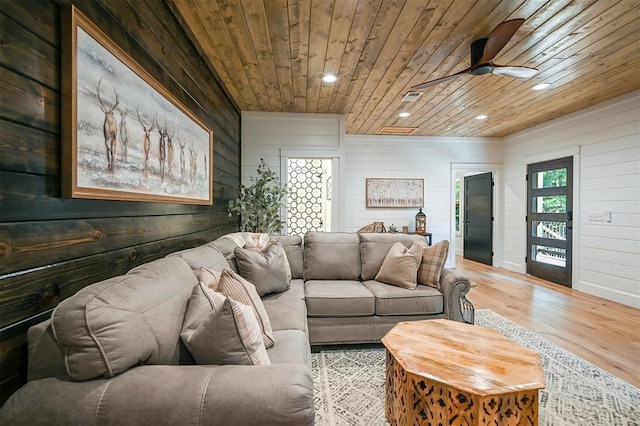 living room with hardwood / wood-style flooring, ceiling fan, wood walls, and wood ceiling