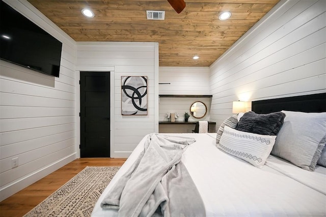 bedroom with light hardwood / wood-style floors, wood ceiling, and wooden walls