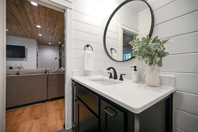 bathroom with wood-type flooring, vanity, wooden ceiling, and wood walls