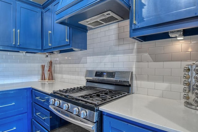 kitchen featuring stainless steel range with gas cooktop, custom range hood, blue cabinets, and tasteful backsplash