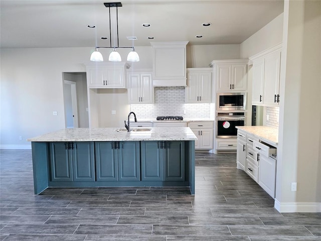 kitchen with pendant lighting, light stone countertops, a kitchen island with sink, and appliances with stainless steel finishes