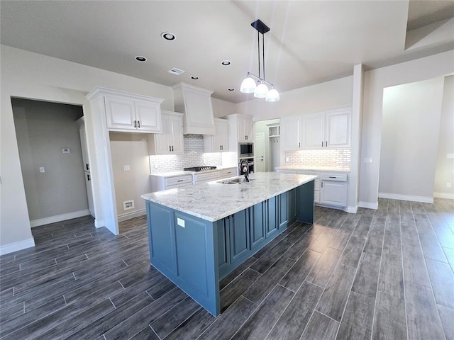 kitchen featuring dark wood-type flooring, sink, appliances with stainless steel finishes, a large island, and white cabinetry