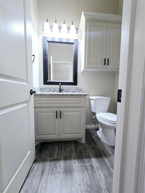 bathroom with hardwood / wood-style flooring, vanity, and toilet